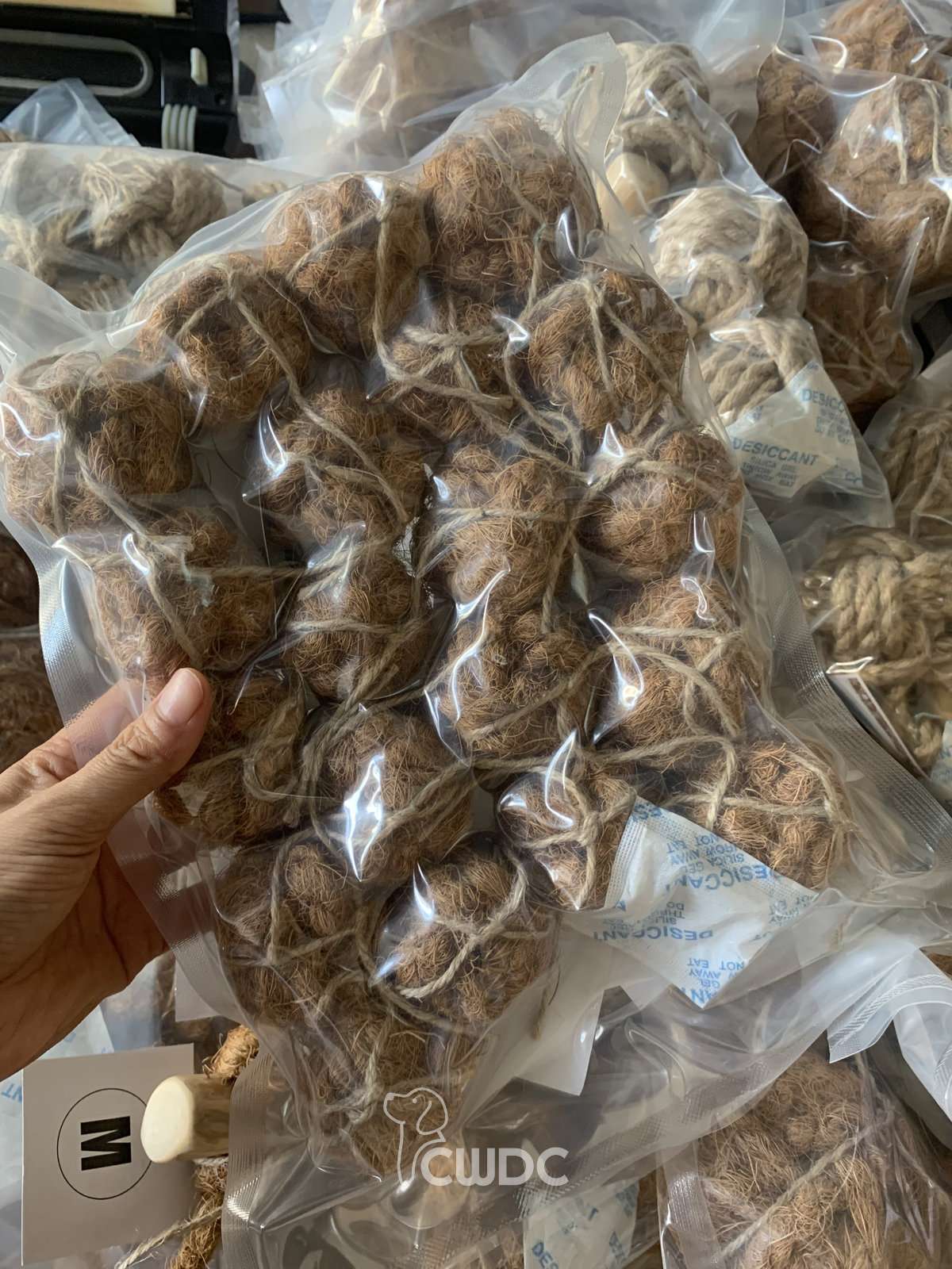 Multiple individually vacuum-sealed coconut coir dog toys with desiccant packets and a size label marked M